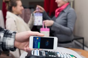 Near Field Communication - Man completing contactless mobile Payment Woman shopping