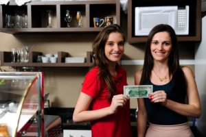 happy owner of a cafe and employee showing cash at the POS