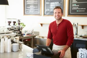 Male Owner Of Coffee Shop in front of POS