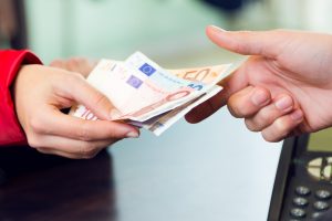 Portrait of woman customer paying with money. Hands detail.