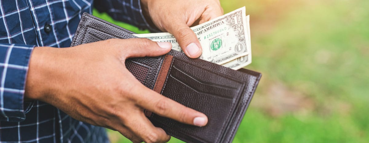 Man pulling a few dollar bills out of his wallet