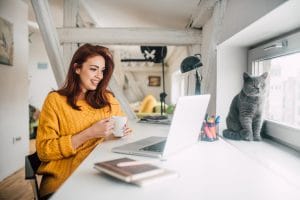 Happy young redhead working on a laptop