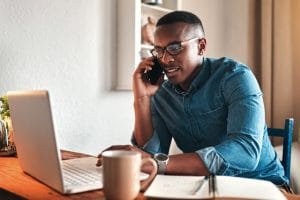 Cropped shot of a handsome young businessman sitting alone in his home office and talking on his cellphone