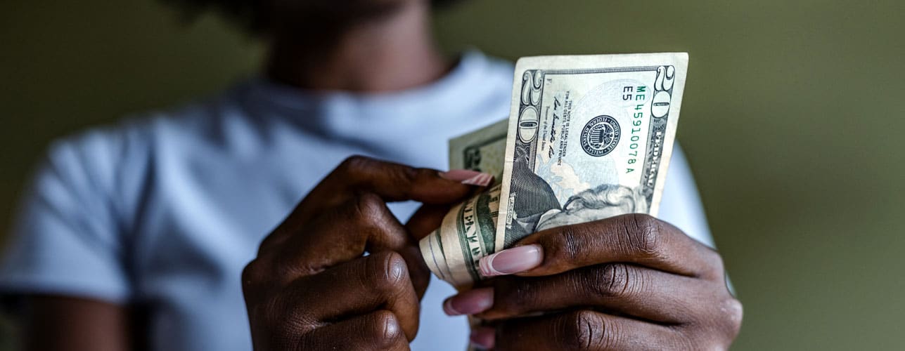 A woman counts a wad of $20 bills