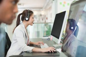 Portrait of confident businesswoman with headset at computer in office